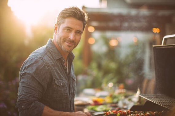 Photo of a male cooking outdoors on a grill