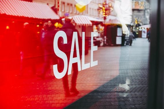 Image of a retail window with a prominent red "sale" sign.