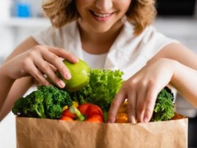 Photo of a female holding grocery produce in a paper sack