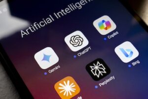 The Google Gemini, ChatGPT, Microsoft Copilot, Claude by Anthropic, Perplexity and Bing apps logos is displayed on the screen of a smartphone