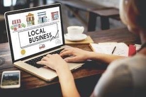 Photo a a lady typing on a laptop screen that says "Shop local"